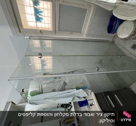 מקלחון זכוכית עם מגבת תלויה וסבונים